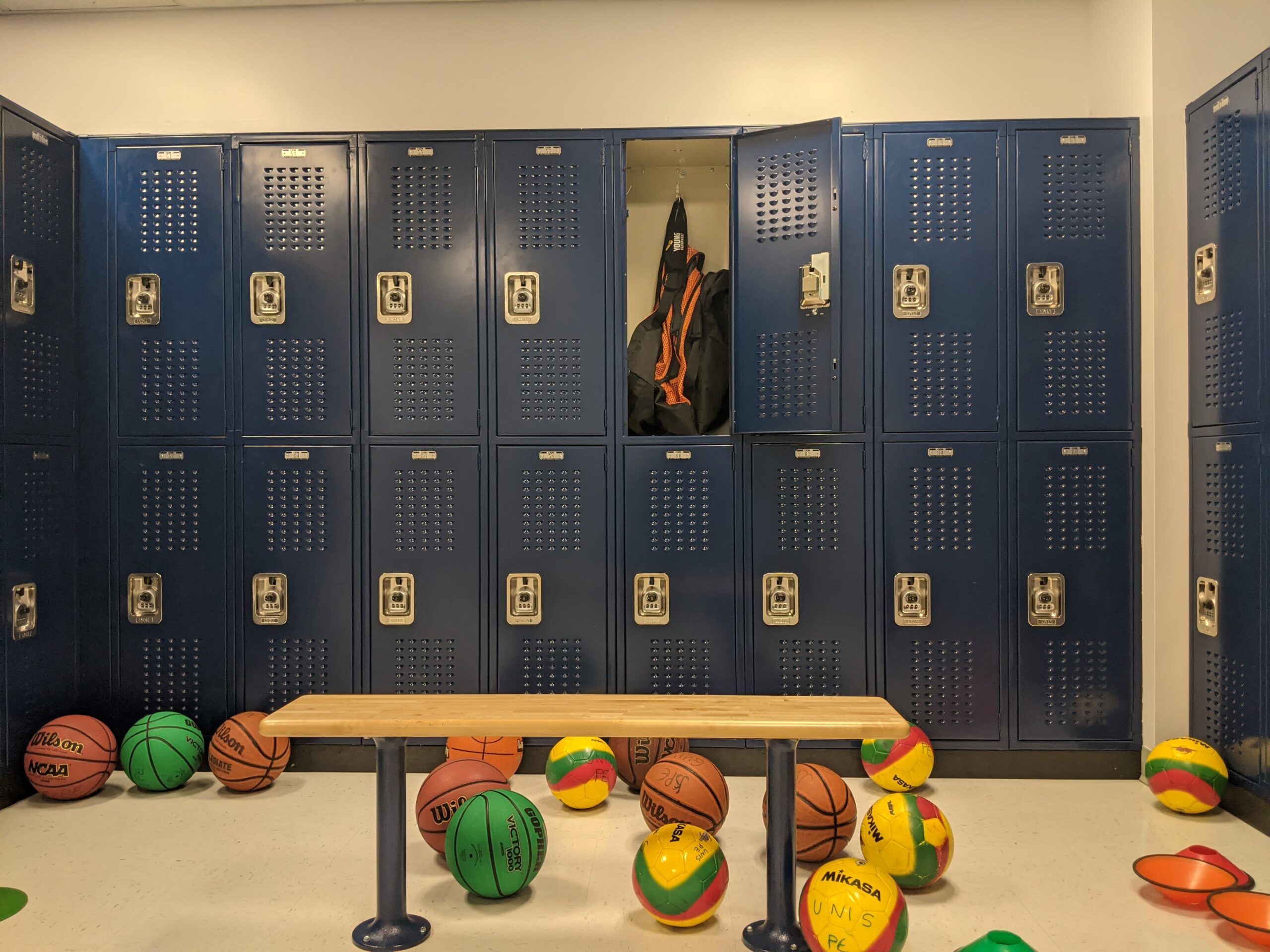 Navy blue vented lockers with one locker open holding a gym bag