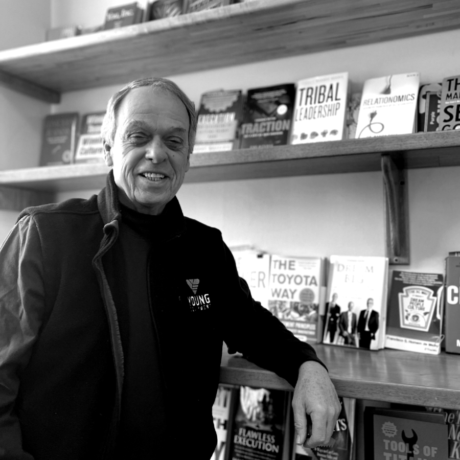 A black and white image of a man resting his elbow on a shelf